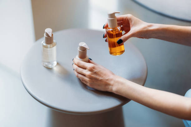 Hands Organizing Cosmetic Bottles for Skin Care Routine on a Minimalist Table