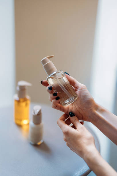 istock Hands Holding a Transparent Cosmetics Bottle With Lotion Containers in Background 2193580278