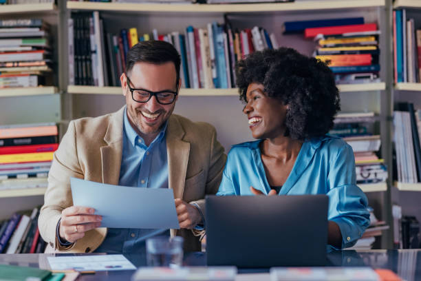 istock Two Professionals Laughing Together While Working and Reviewing Documents in an Office 2193581100