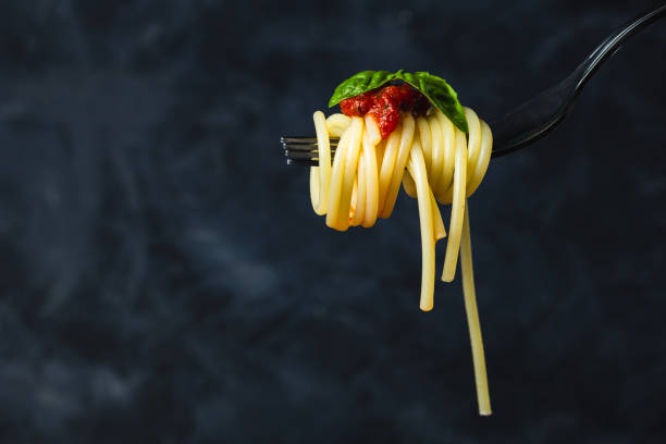 istock Italian spaghetti on fork on dark background. Close up. 2193582050