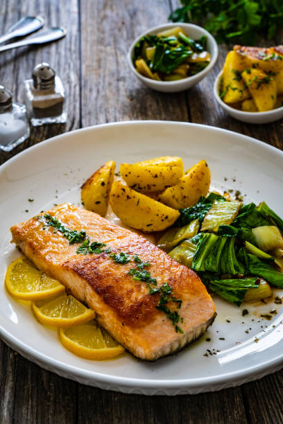 istock Fried salmon, fried potatatoes with stir-fried bok choy on wooden table 2193587875