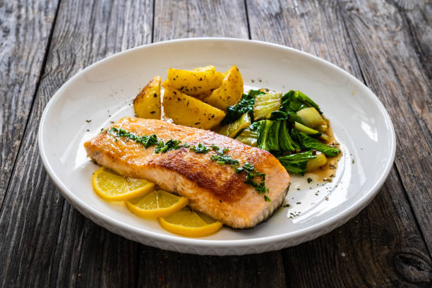 istock Fried salmon, fried potatatoes with stir-fried bok choy on wooden table 2193587883
