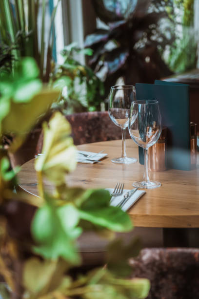 istock Empty wine glasses resting on wooden restaurant table surrounded by lush greenery 2193588524