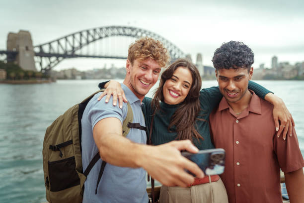 Three cheerful friends taking selfie with Sydney Harbour Bridge at the background