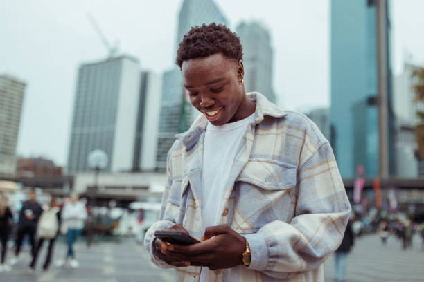 Cheerful casually clothed man using smart phone outdoors at Sydney