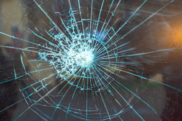 Cracked glass surface with intricate patterns illuminated by light, showcasing a dramatic burst effect stock photo