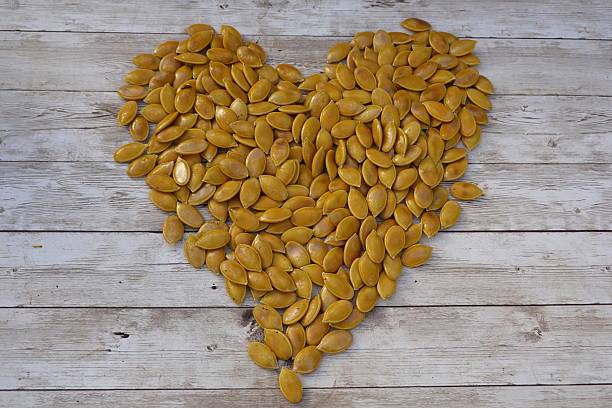 istock Pumpkin seeds forming a heart shape on rustic wooden table 2193589942