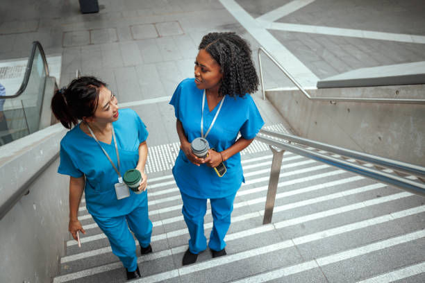 istock Two female nurses walking on stairs with coffee cups in their hands 2193590400