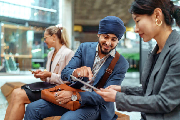 istock Two smiling colleagues using digital tablet while sitting on a bench at city downtown 2193590917