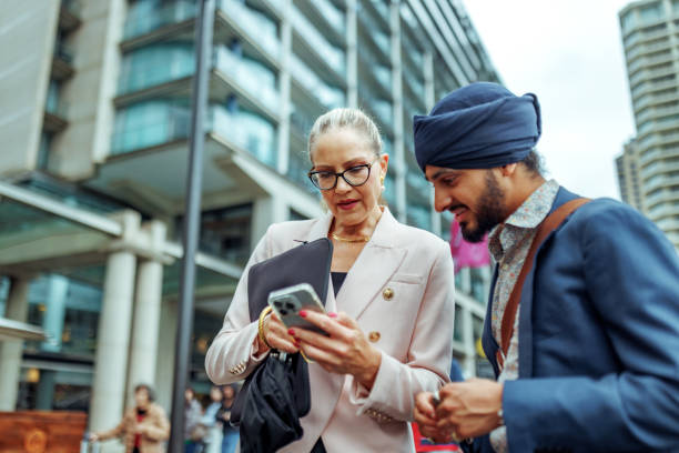 istock Two diverse business colleagues using smart phone while talking outdoors at the city of Sydney 2193590991