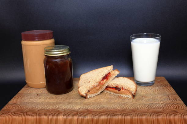 Peanut butter and jelly sandwich, being made on a cutting board before a black background