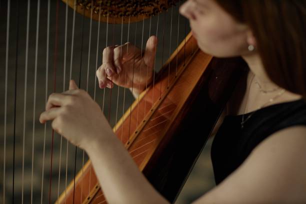 istock Hands of Female Musician Playing Harp Strumming Strings during Performance Indoors 2193593597