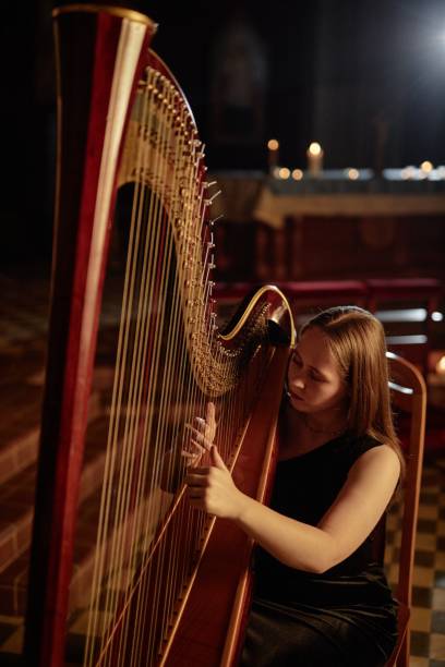 istock Female Musician Playing Harp Strumming Strings Softly during Performance in Church 2193593682
