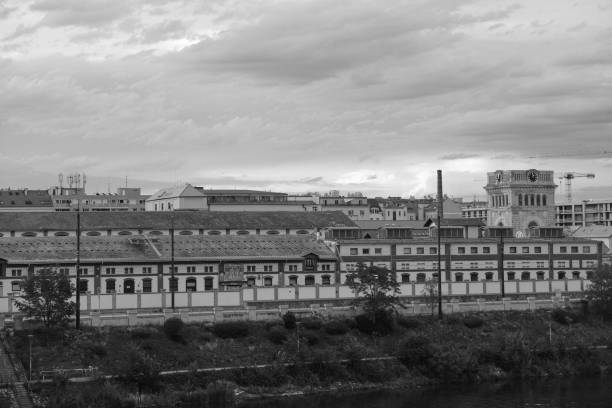 House along a river in urban area in Prague historic zone with sky in the background in black and white style with architecture monuments in the background
