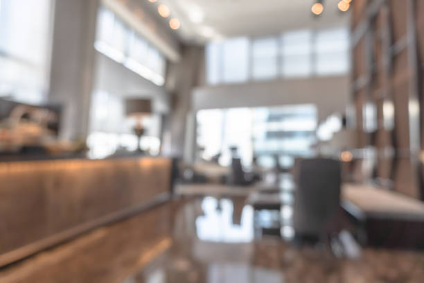 Blurred hotel or office building lobby blur background interior view toward reception hall, modern luxury lounge, white room space with blurry corridor and building glass wall