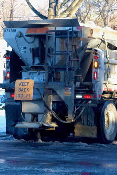 Fairfax, Virginia, USA - January 11, 2025: A Virginia Department of Transportation (VDOT) snowplow works to remove slush and ice from a neighborhood road in suburban Northern Virginia following Winter Storm Blair.