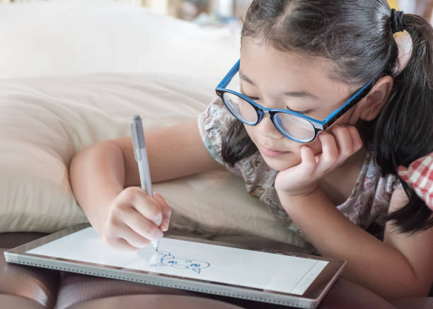 istock School child girl kid using internet online learning on mobile tablet reading looking at digital screen for educational study for Childrenâs Eye Health and Safety Month and Blue Light Awareness Day 2193599497