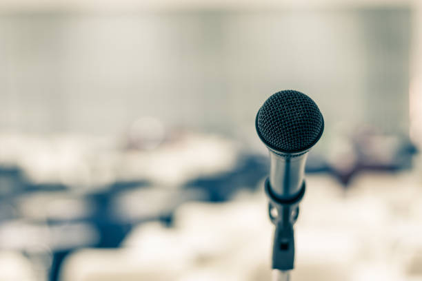 istock Microphone voice speaker in seminar classroom, lecture hall, town hall meeting or conference forum in educational business event for coaching host or teacher with audiences or students seats 2193599508