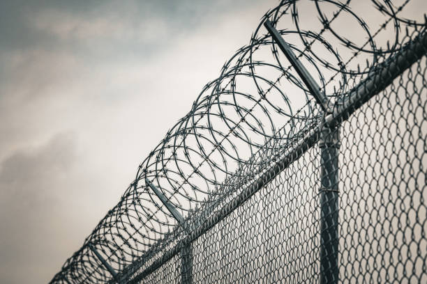 istock Barbed Wire Fence Against a Cloudy Sky Depicting Security and Restriction 2193604590