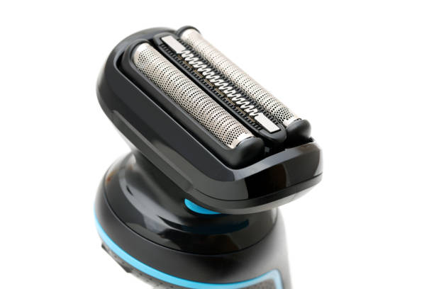Mid adult man is shaving his head with an electric razor while looking in the bathroom mirror