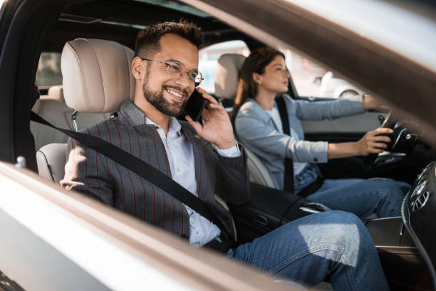 istock Happy businessman using phone while traveling in car with female driver 2193615470