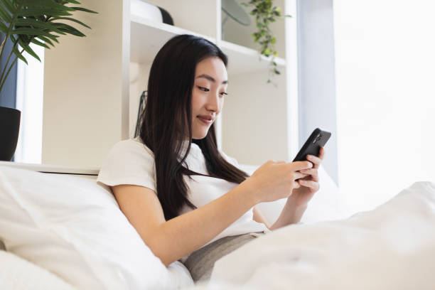 istock Young Asian woman using smartphone in modern bedroom 2193619952