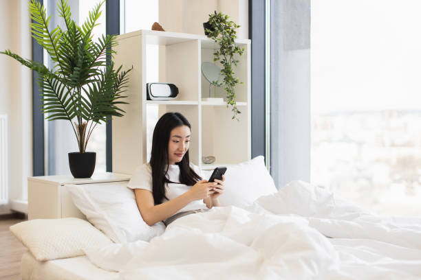 istock Young Asian woman using smartphone in modern bedroom 2193619970