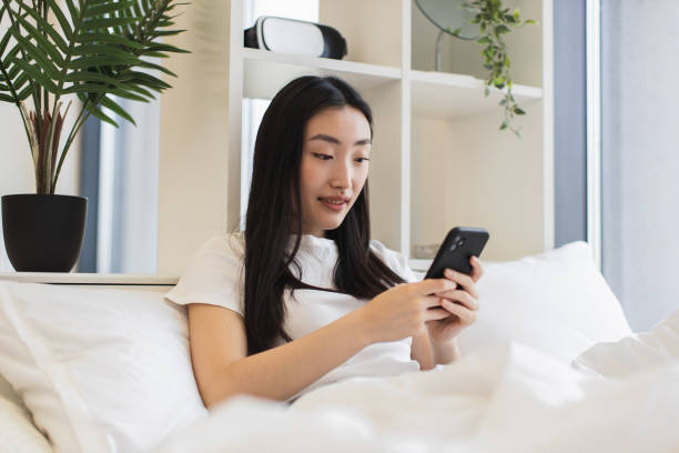 istock Young Asian woman using smartphone in modern bedroom 2193619971