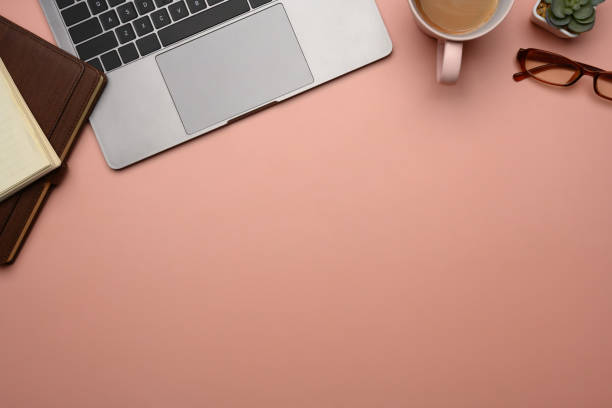 istock Above view feminine workspace with laptop, notebook, coffee cup and plant on pink background 2193620510