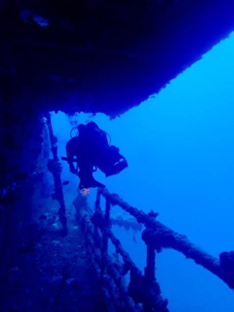 istock Scuba Diver Exploring a Sunken Shipwreck in Deep Blue Ocean 2193627724