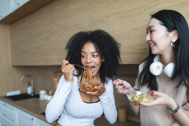 istock Two female friends eating salads at the kitchen and talking 2193629042