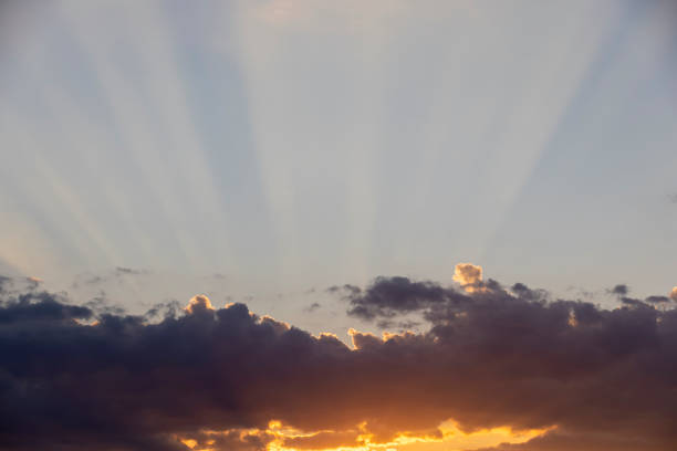 sky with clouds at sunset, the sun's rays shine through the clouds on the sky background during sunset at dusk