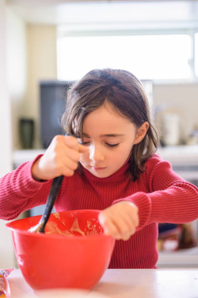 istock Girl Scooping Dough from Mixing Bowl 2193634503