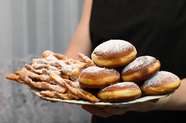 istock Freshly fried doughnuts and angel wings sprinkled with icing sugar on a plate close-up 2193634811