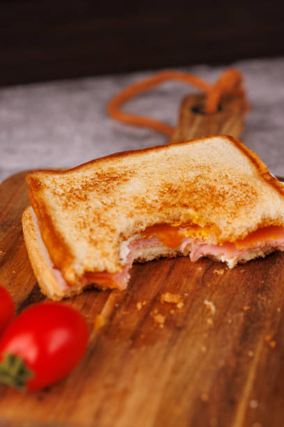 istock Rustic Egg, Ham, and Cheese Sandwich with Cherry Tomatoes on a Dark Cutting Board 2193636444