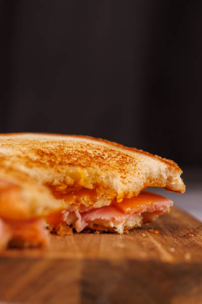 istock A satisfying half-eaten sandwich of egg, ham, and cheese is displayed on a vertical tower, alongside fresh cherry tomatoes on a gray table 2193636519