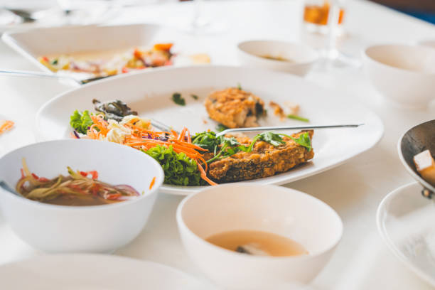 leftover food on white plastic plate in soft focus with blurred used fork, bowl