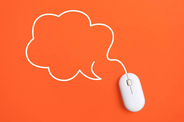 For communication concept, top view of white computer wireless mouse with blank speech bubble cloud shape on orange background, copy space included