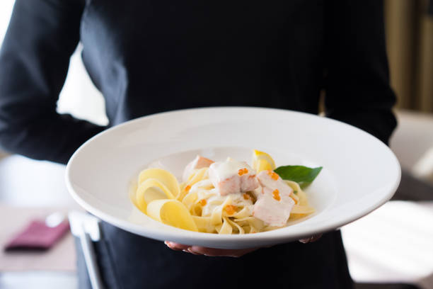 Close-Up of Gourmet  Salmon Pasta Dish on a Chefs or waitress hands