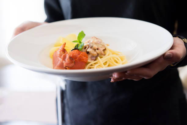 Close-Up of Gourmet  Bacon Pasta Dish on a Chefs or waitress hands