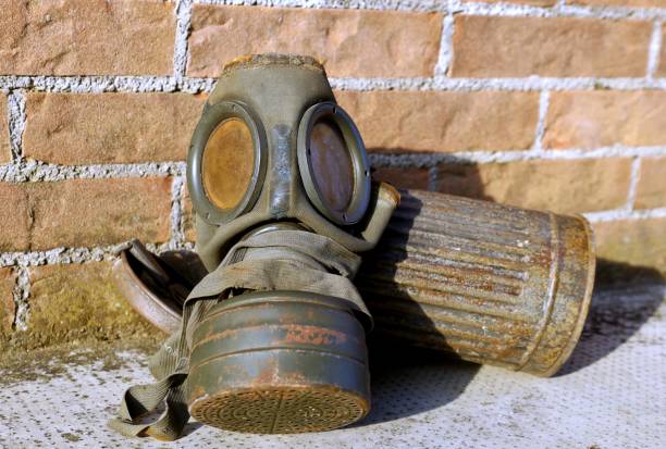 istock Worn and rusty german Army old gas mask and its container. Brick wall on background 2193643617