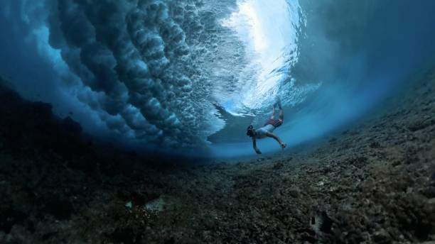 istock Man with mask dives under the breaking ocean wave 2193645072