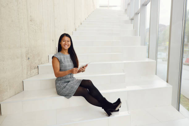 istock Happy Asian businesswoman using touchpad on staircase in a hallway. 2193645484