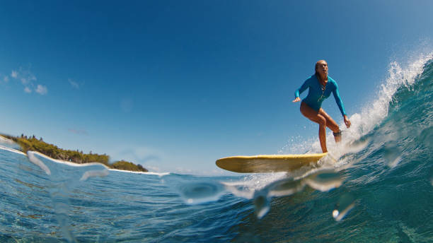 Athletic woman surfing waves on yellow surfboard