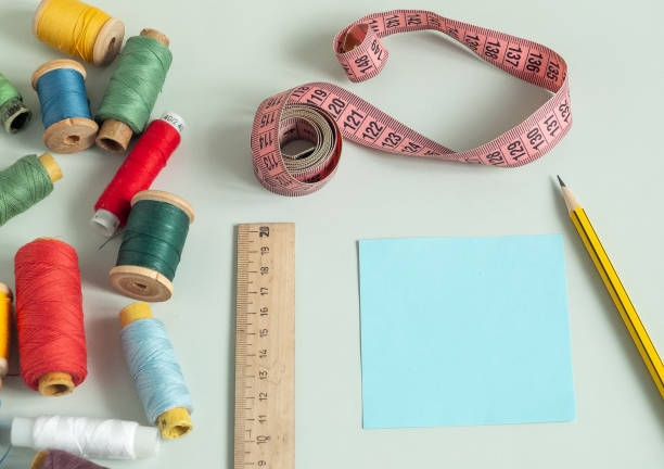 istock Background for sewing. Needlework supplies on a light background. Spools of thread, scissors, buttons, measuring tape, sewing accessories. notebook 2193650903