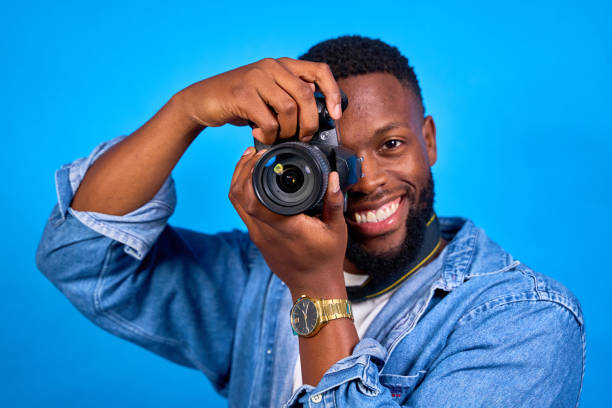 istock Young photographer smiling and taking photos on blue background 2193654124