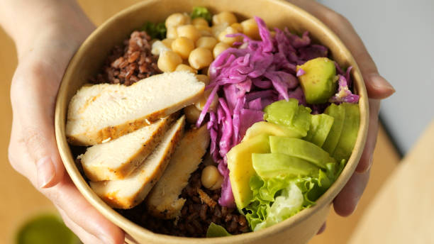 istock Human hands grasping vibrant salad poki bowl containing grilled chicken, avocado, red cabbage, chickpeas, lettuce, brown rice representing nutritious, wholesome eating 2193655284