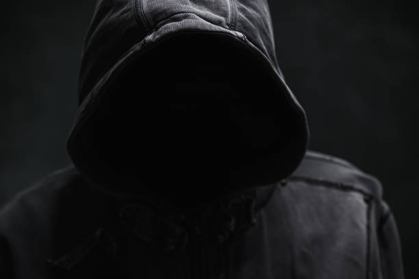istock Unrecognizable cyber criminal or computer hacker wearing black hooded jacket, low key portrait 2193655800