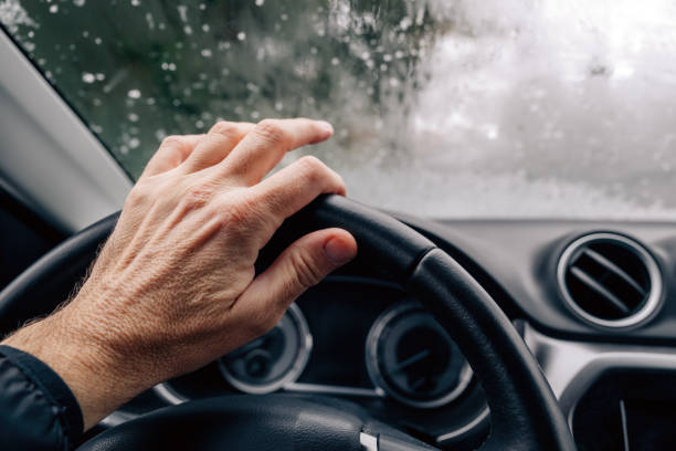 Male hand on a car steering wheel on cold winter day, selective focus