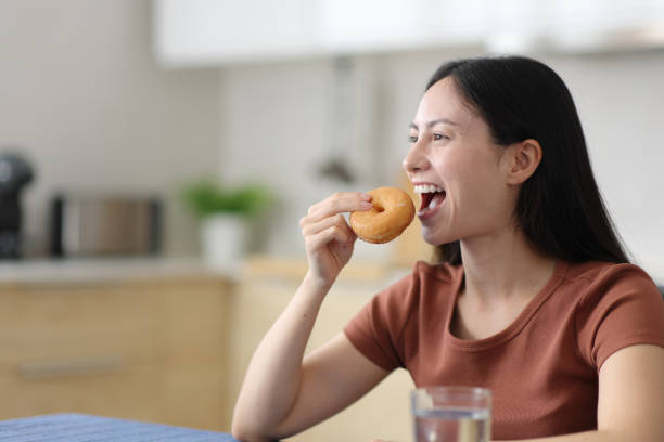 istock Asian woman eating doughnut in the kitchen 2193656041